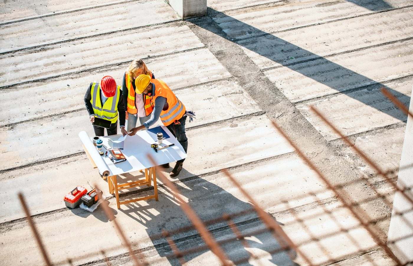 Équipe d'ingénieurs en réunion de chantier sur dalle béton